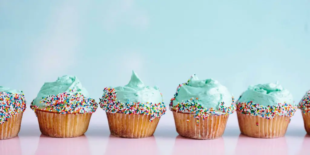 six teal icing cupcakes with sprinkles