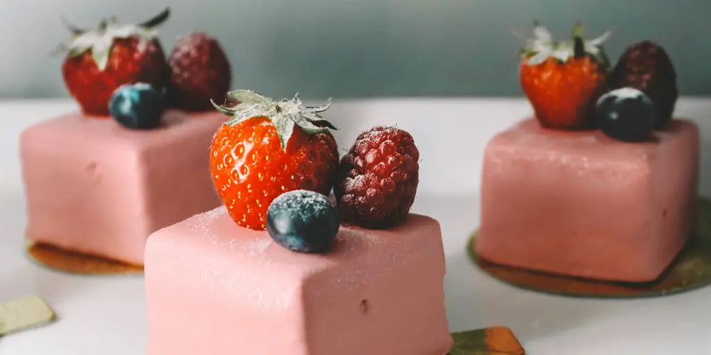 three square pastry with strawberries on top platter